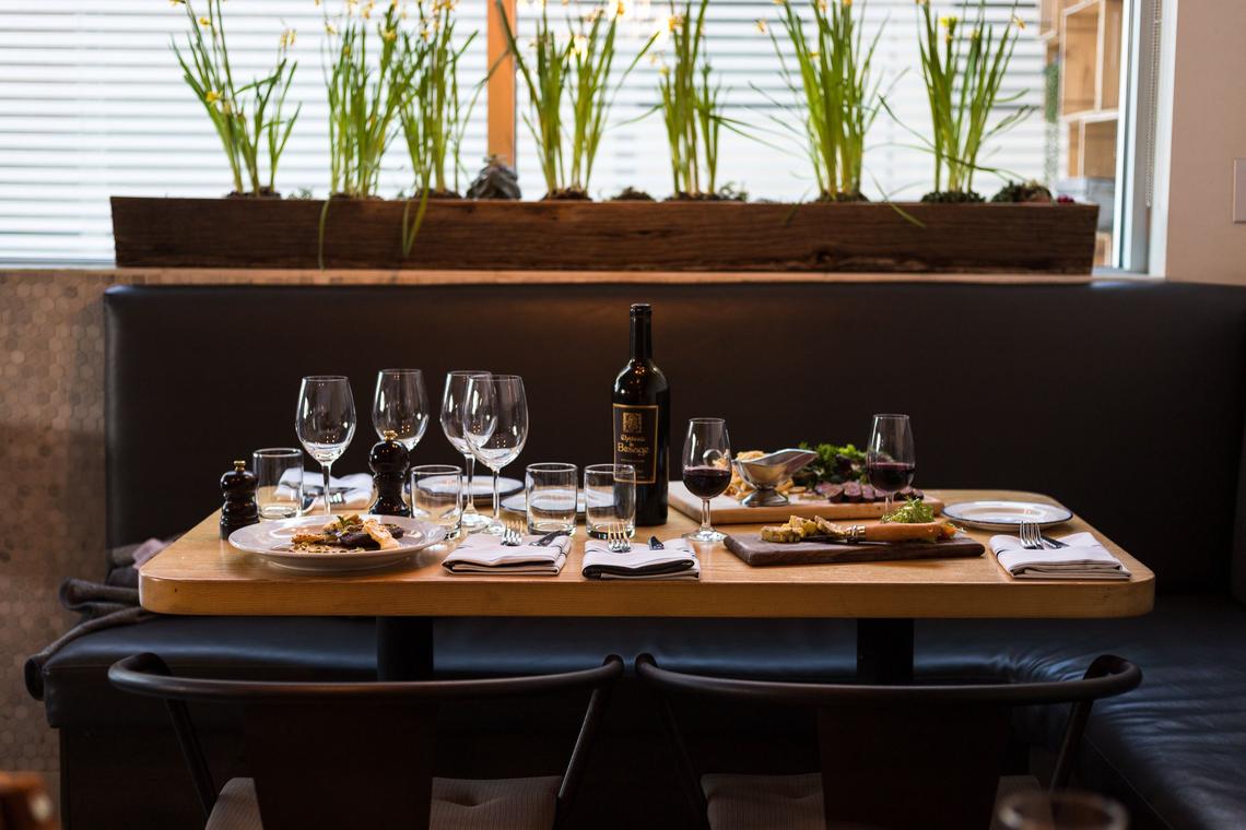 Beautiful corner table set for dinner. Surrounded by living plants.